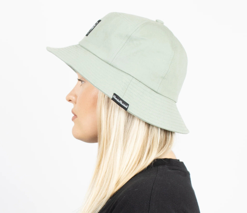 3. Woman smiling in light green Stinky Bucket Hat by Moomin, studio setting