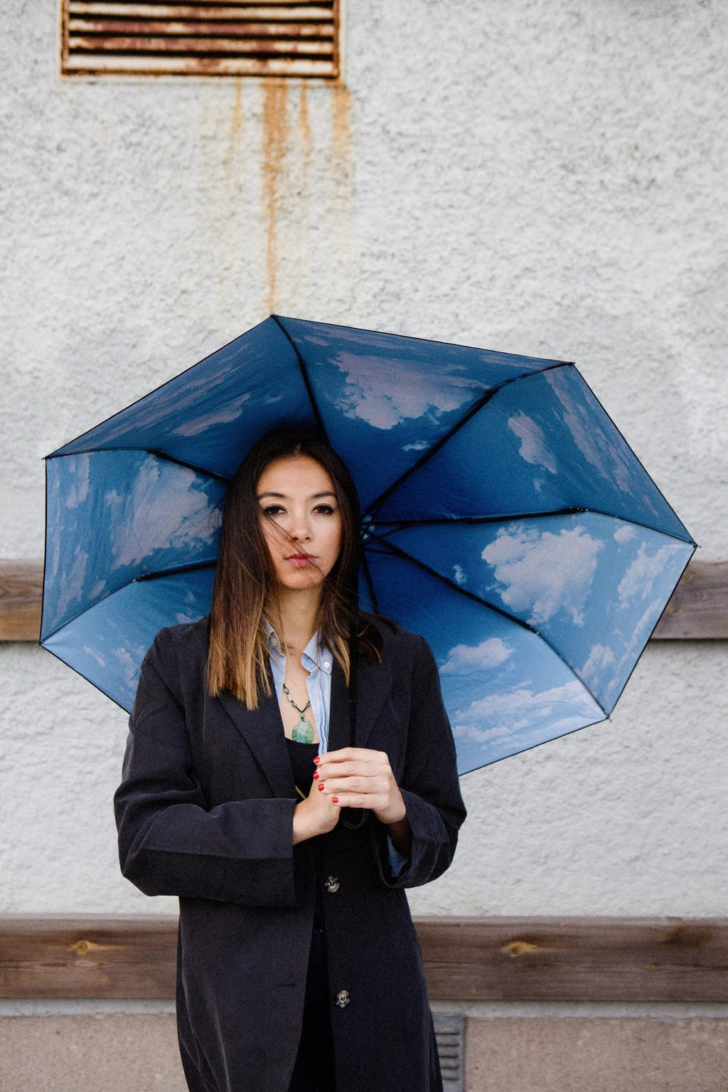 10. Woman holding Sky Lake umbrella with blue cloud print, standing against wall
