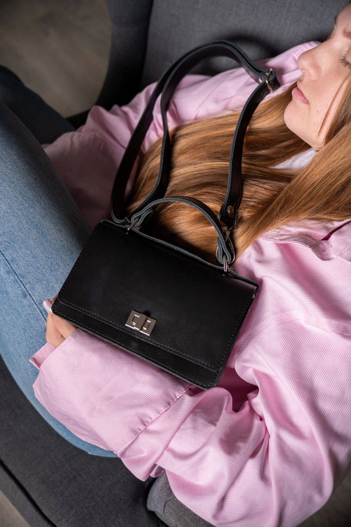 14. Woman resting with Zelma Kraft black handbag, showcasing silver clasp and strap