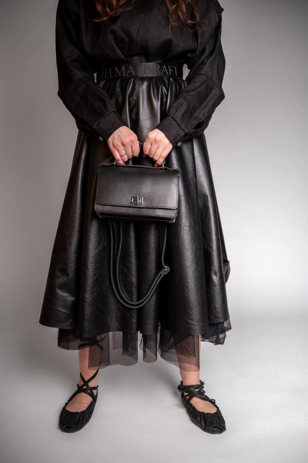 7. Woman in black dress holding Zelma Kraft black small briefcase handbag