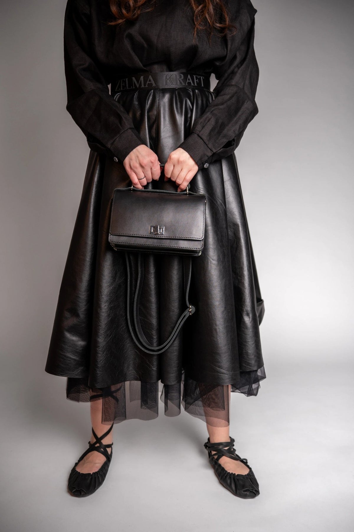 7. Woman in black dress holding Zelma Kraft black small briefcase handbag