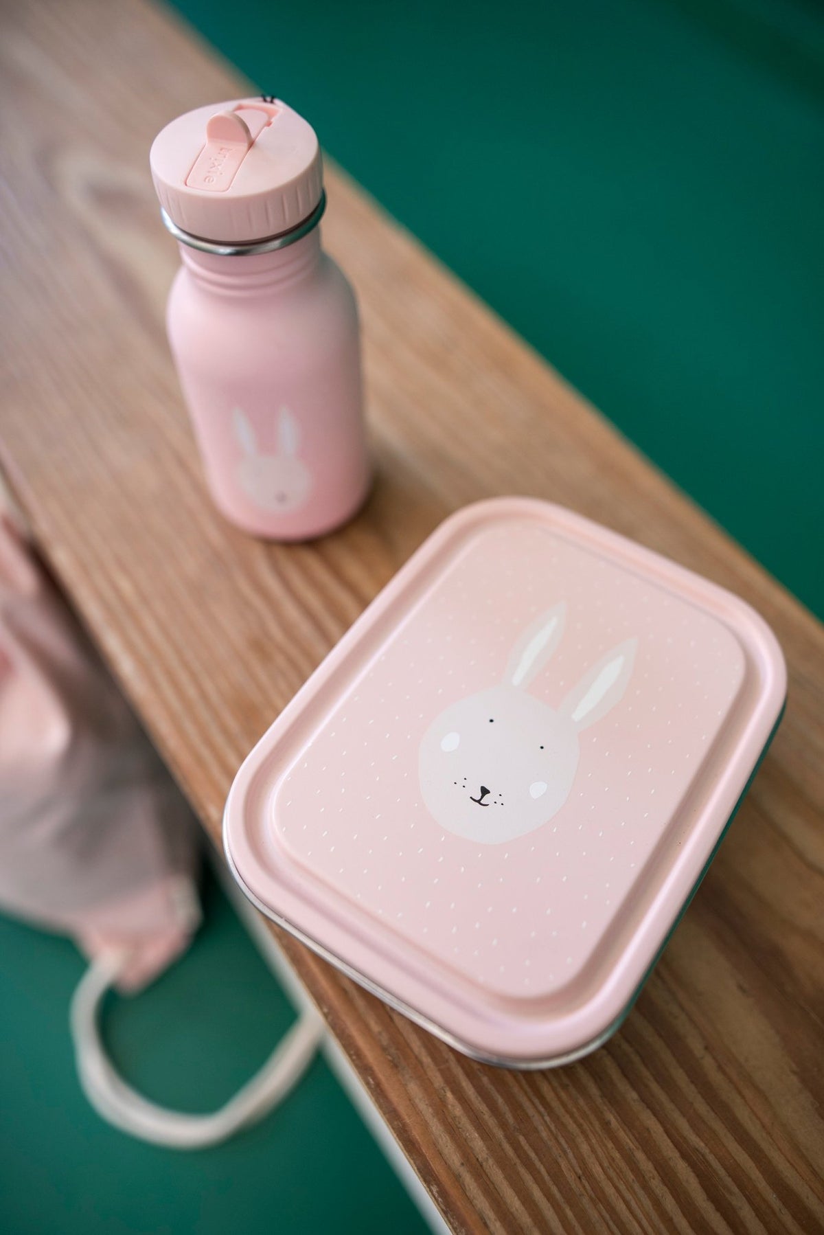 1. Pink Mrs. Rabbit lunch box and matching bottle on wooden bench, highlighting playful design for kids