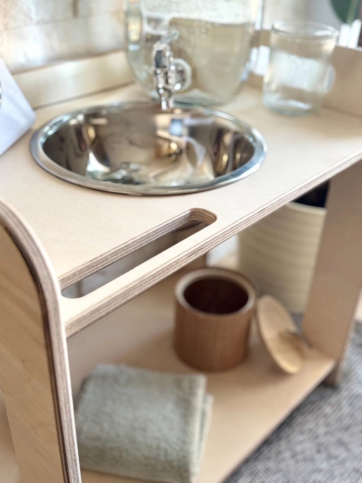 3. Close-up of wooden wash station with enamel bowl, towel, and wooden container on shelf