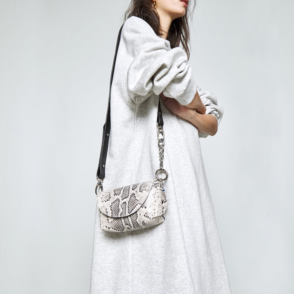 9. Woman holding Daz Studio snake print leather shoulder bag, highlighting the elegant design