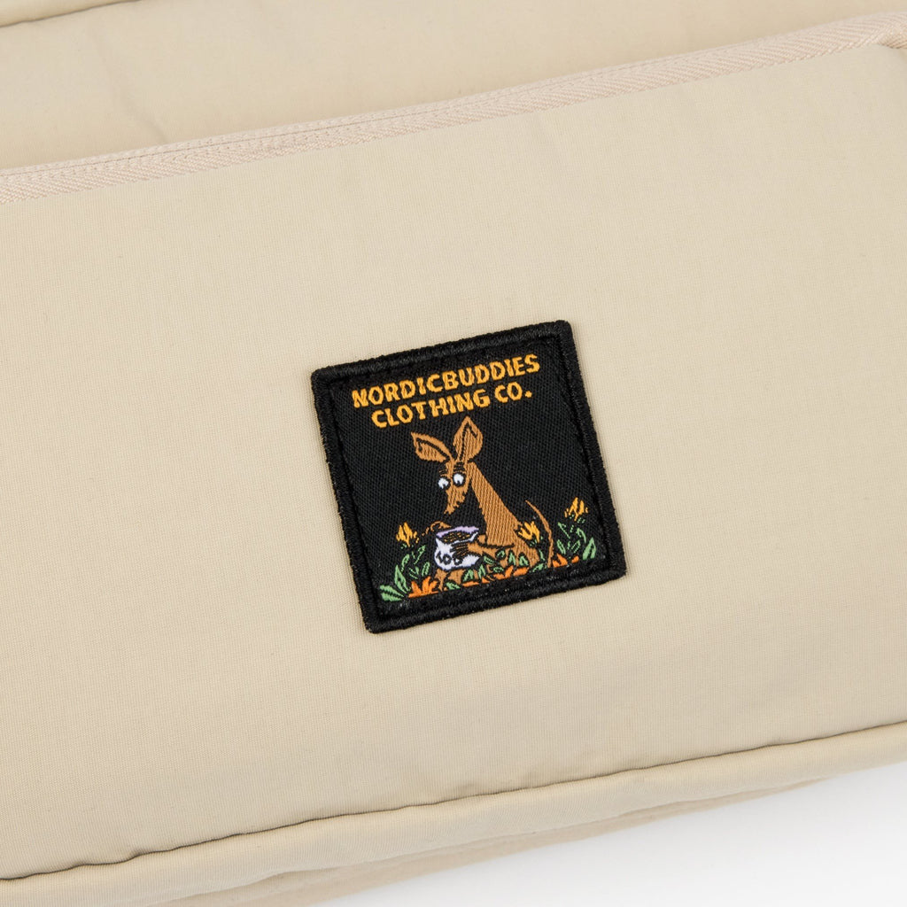 3. Close-up of NordicBuddies Clothing Co. logo patch on beige Sniff Retro Waist Bag