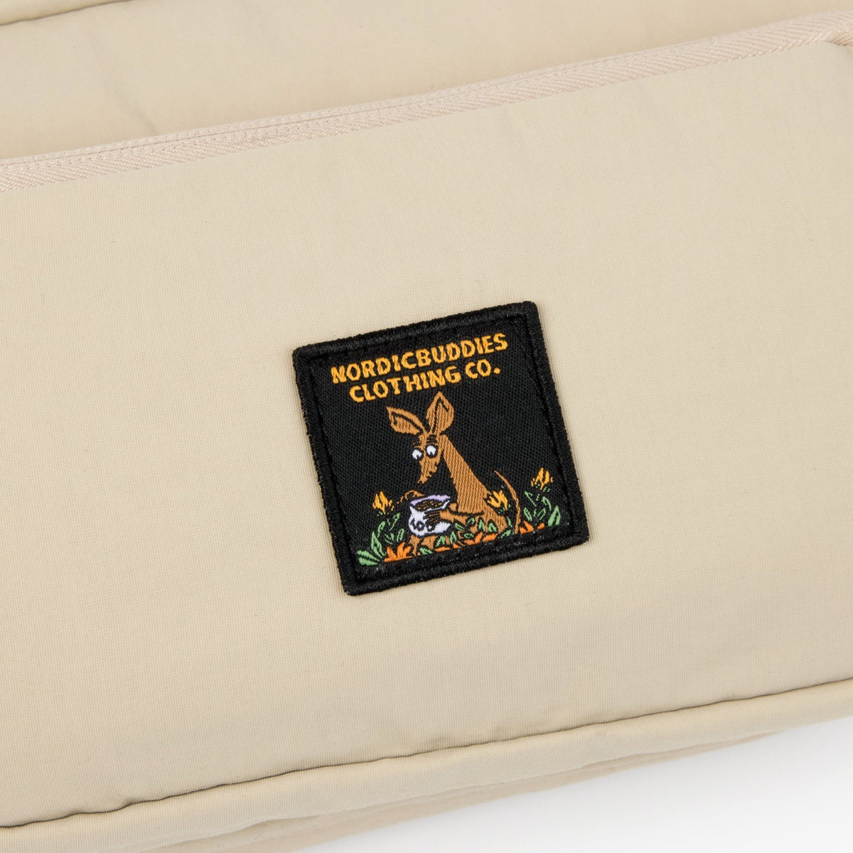 3. Close-up of NordicBuddies Clothing Co. logo patch on beige Sniff Retro Waist Bag
