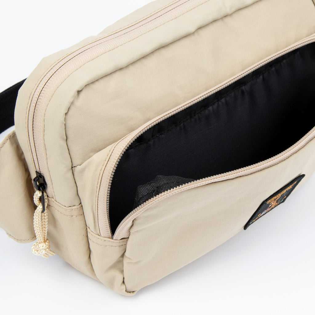 3. Open front pocket of beige Sniff Retro Waist Bag showing black interior and zipper detail