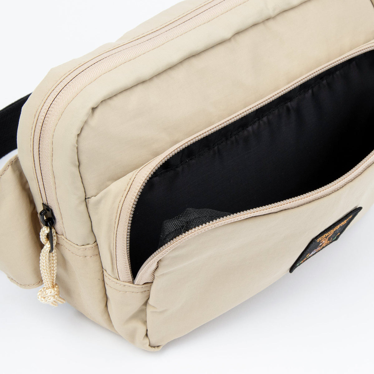 3. Close-up of front pocket on beige Sniff Retro Waist Bag with black interior