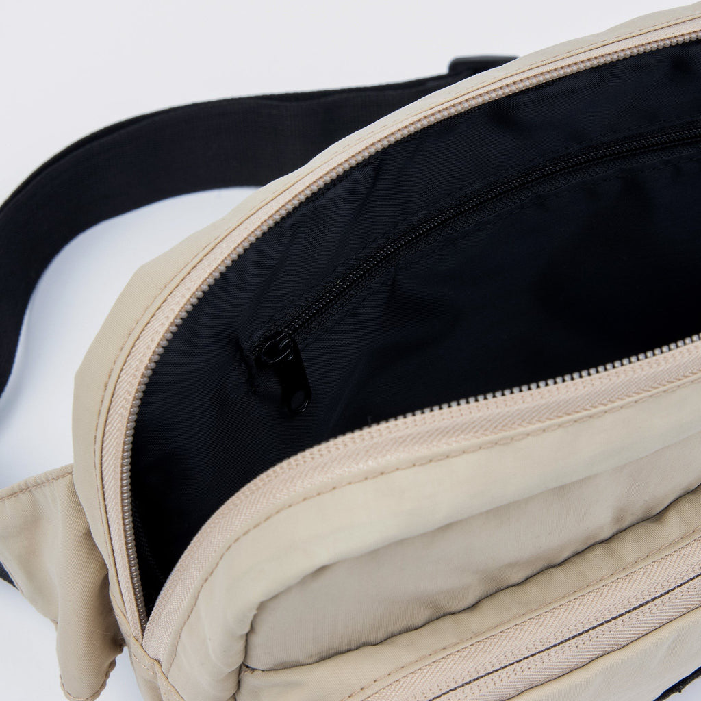 3. Interior view of beige Sniff Retro Waist Bag showing black lining and zipper