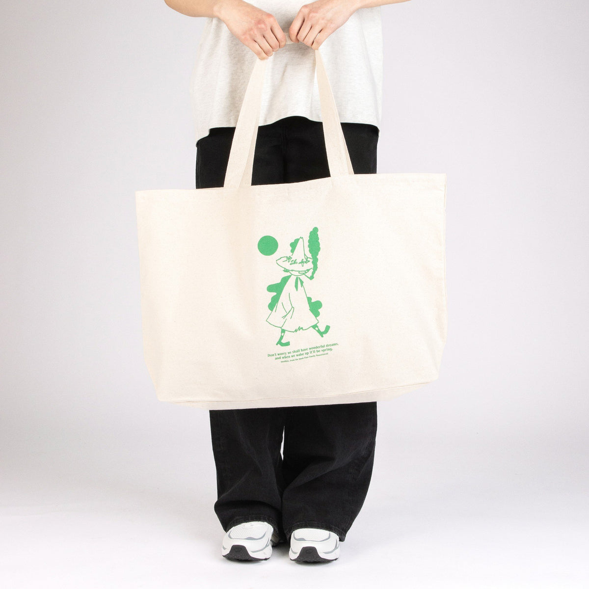 1. Woman holding Moomin by NordicBuddies Snufkin XXL tote bag in studio setting