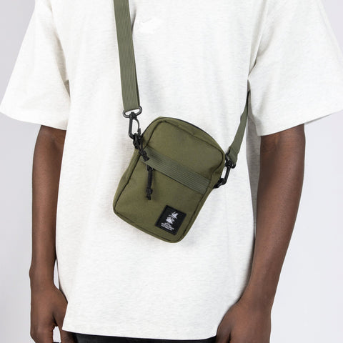 1. Person wearing green Snufkin travel cross body bag by Moomin NordicBuddies over white t-shirt