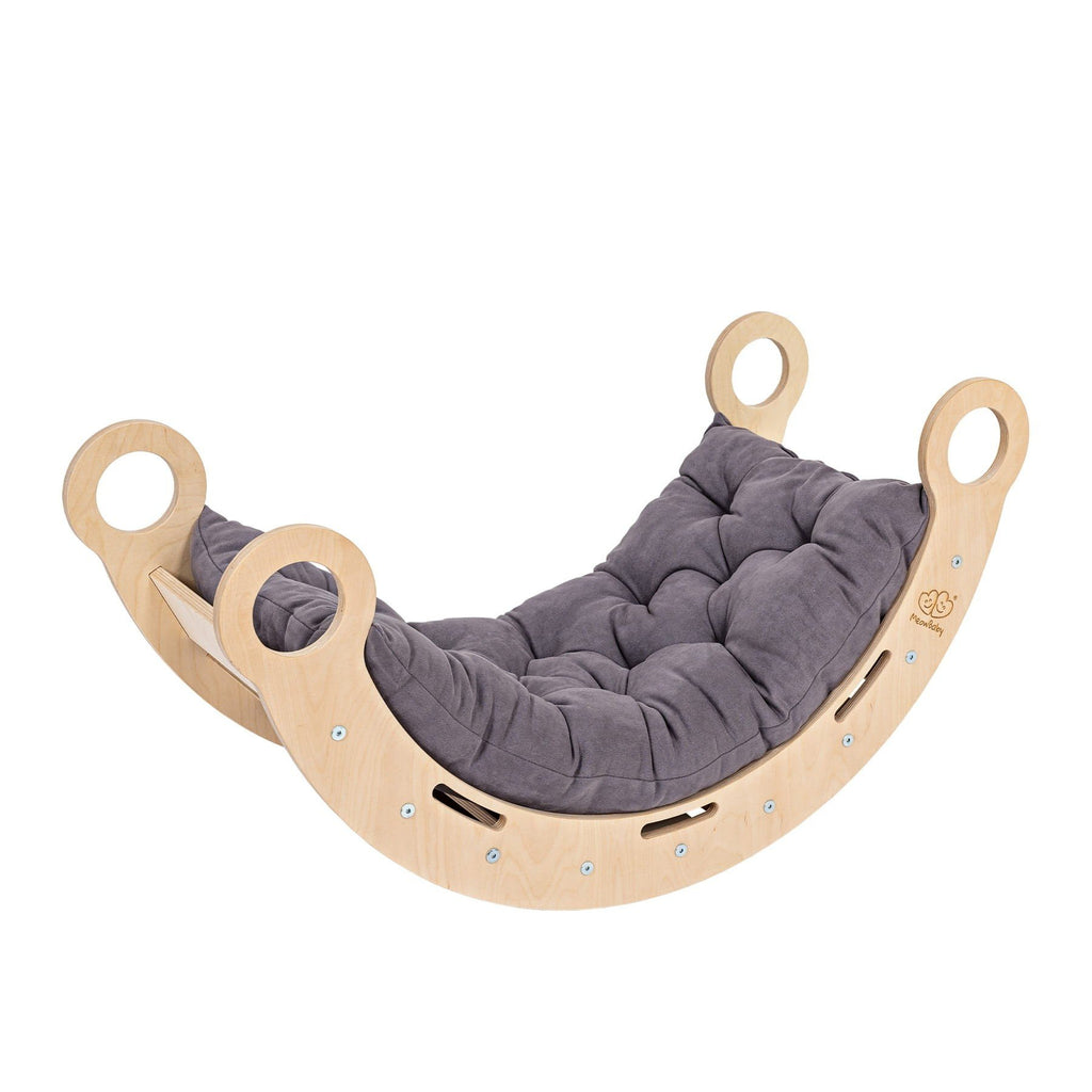 7. Snug Rocker for kids in natural birch plywood with grey pillow, featuring rounded edges and handles, shown from an angle