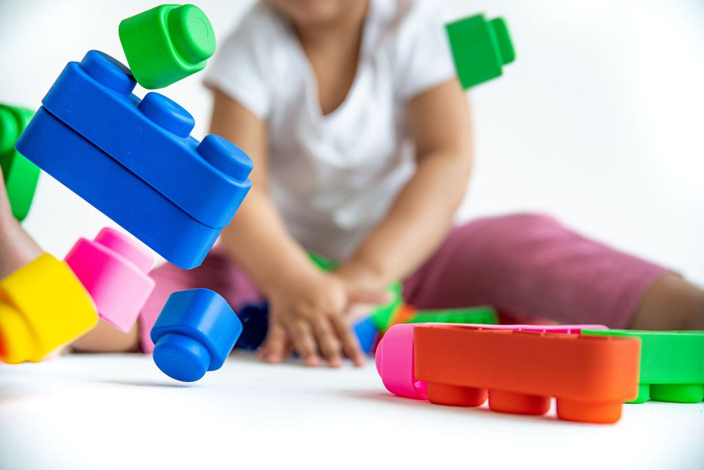 1. Toddler playing with colorful soft blocks, enhancing creativity and motor skills on a white background.
