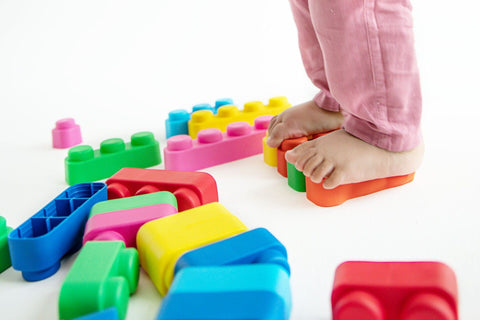 5. Close-up of child's feet stepping on colorful soft blocks on a white background