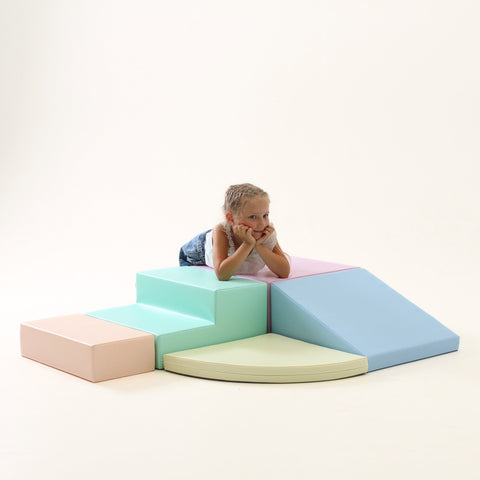 5. Child leaning on IGLU pastel foam block set with steps and ramp in a playroom