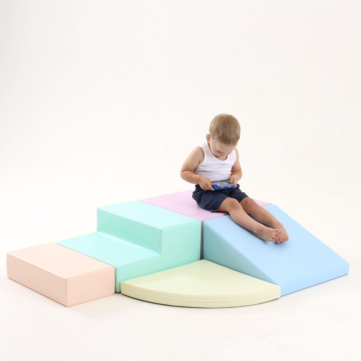 13. Boy sitting on IGLU pastel foam block set with steps and ramp in a studio