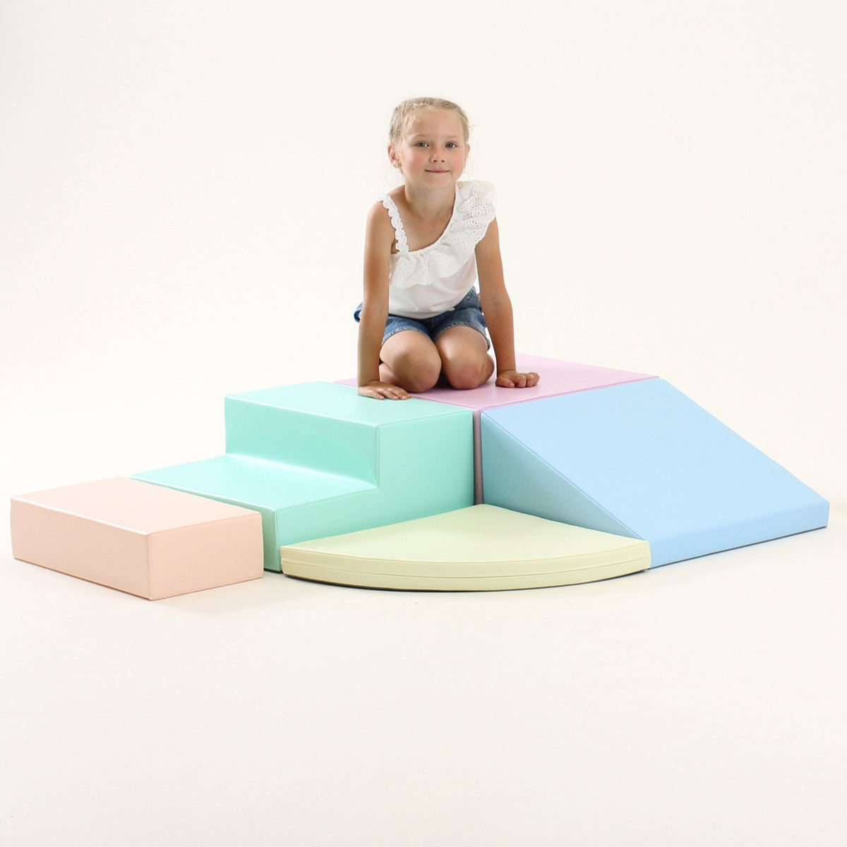 2. Girl sitting on IGLU pastel foam block set with steps and ramp in a studio setting