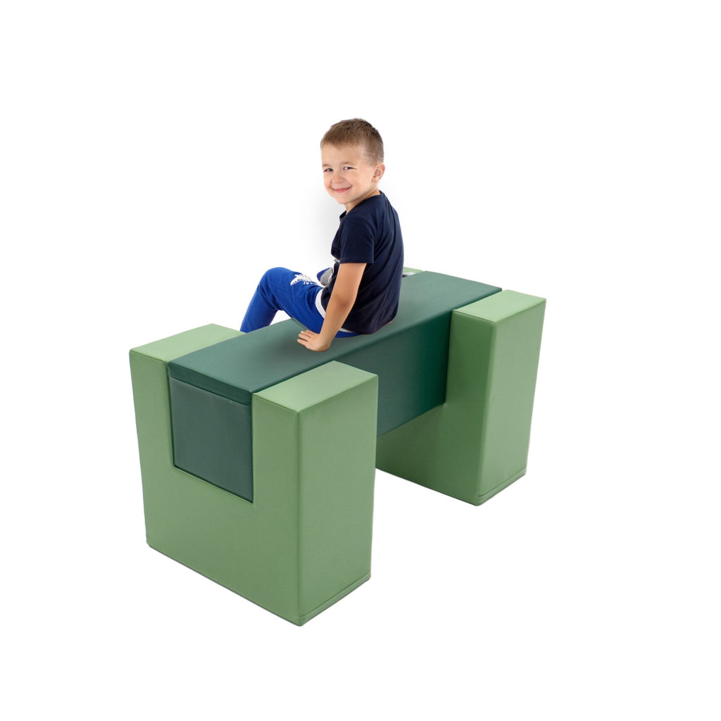 1. Child sitting on IGLU green soft play balance bridge in a studio setting, smiling and wearing casual clothes