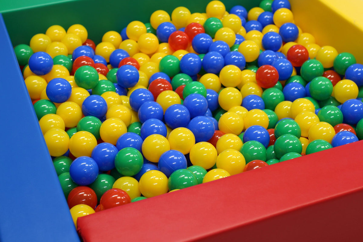 1. Multicolor soft play ball pit filled with red, blue, yellow, and green plastic balls in a colorful play area, ideal for children's sensory play and motor skill development.