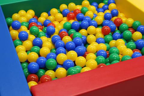 1. Multicolor soft play ball pit filled with red, blue, yellow, and green plastic balls in a colorful play area, ideal for children's sensory play and motor skill development.