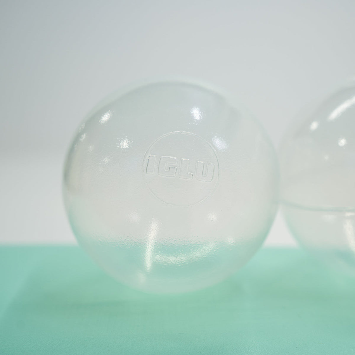 2. Single translucent IGLU soft play ball on light green surface, highlighting logo and smooth finish
