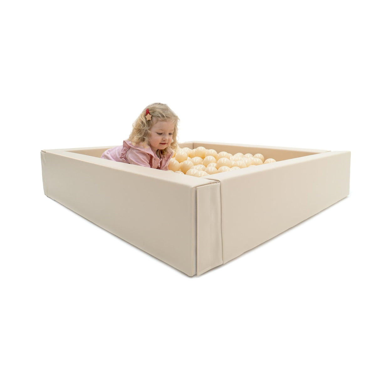 1. Child peeking over edge of beige IGLU soft play ball pit filled with cream-colored balls