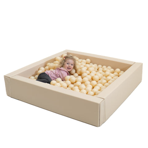 1. Child playing in beige IGLU soft play ball pit filled with cream-colored balls