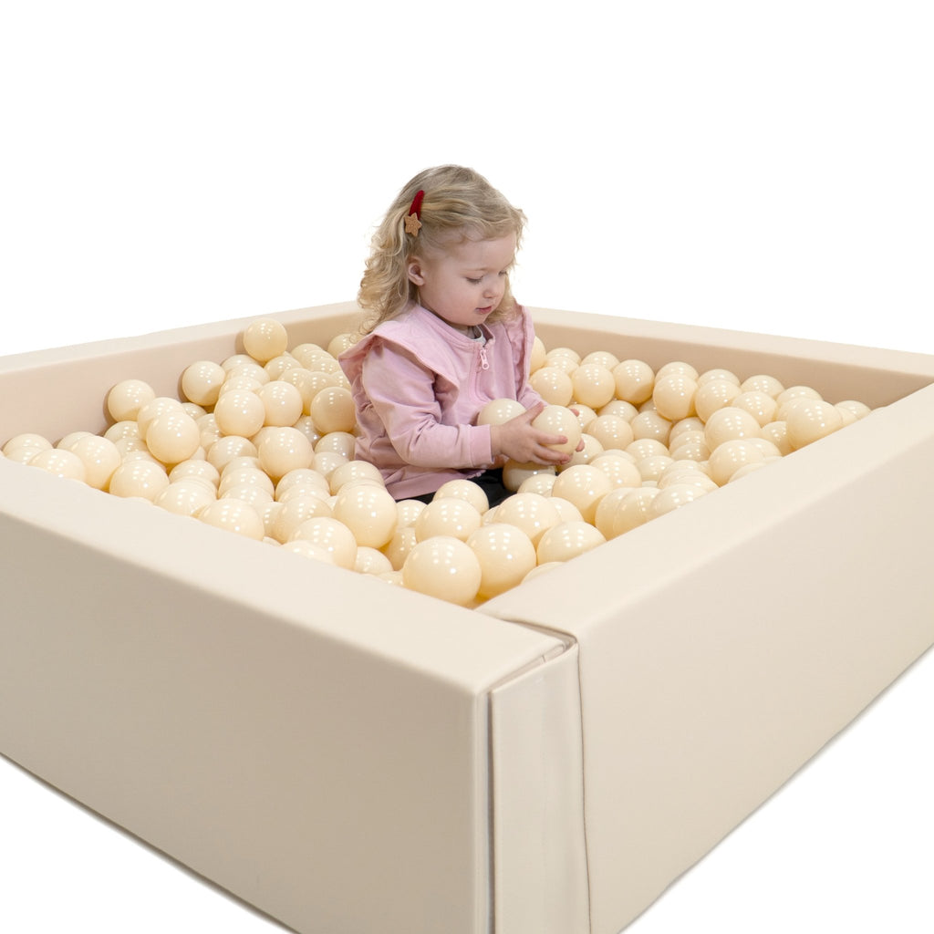 1. Toddler sitting in beige IGLU soft play ball pit with cream-colored balls