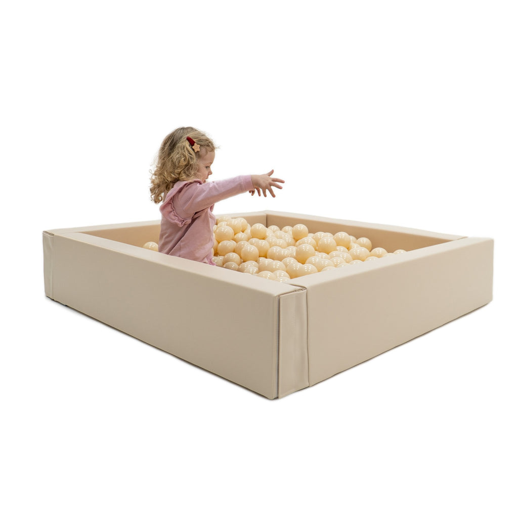 1. Child reaching out while sitting in beige IGLU soft play ball pit with cream-colored balls