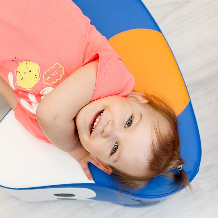 3. Close-up of girl lying on IGLU blue soft play ride-on toy car with orange wheels