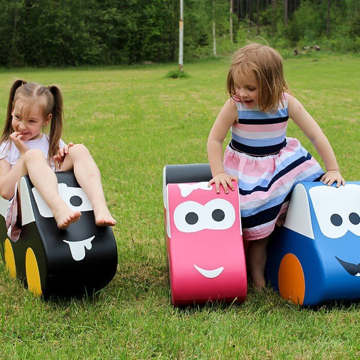 1. Two girls playing on IGLU soft play ride-on toy cars in black, pink, and blue on grass