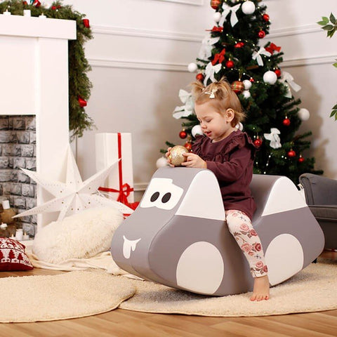 2. Child in maroon outfit playing on IGLU grey car-shaped soft play toy near Christmas tree, enhancing holiday fun