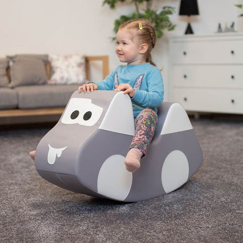 1. Young girl in blue top and floral leggings riding IGLU grey car-shaped soft play toy indoors, smiling and enjoying playtime