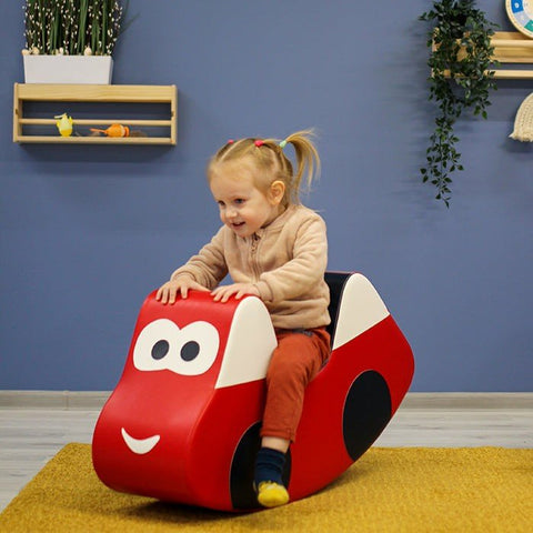 1. Young girl riding IGLU red soft play car toy indoors, smiling and enjoying playtime