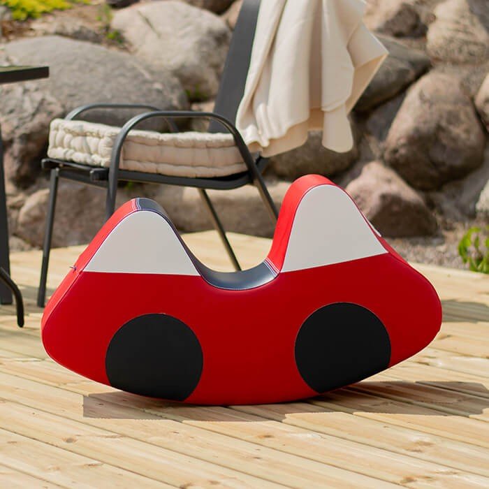 7. IGLU red soft play ride-on car toy placed outdoors on a wooden deck