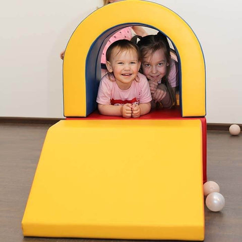 1. Two children smiling inside multicolor soft play tunnel set with yellow slide