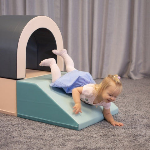 1. Girl sliding down ramp of IGLU pastel soft play tunnel set on grey carpet