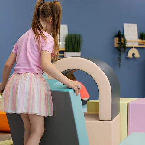 1. Girl climbing on IGLU pastel soft play tunnel set in colorful playroom