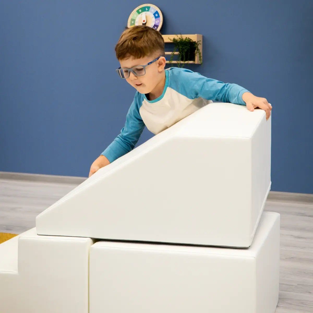 12. Boy climbing white IGLU soft play set ramp in playroom with blue wall
