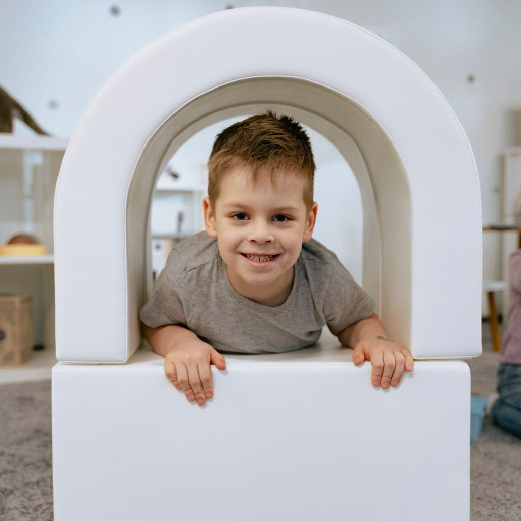 7. Smiling boy crawling through white IGLU soft play tunnel in playroom