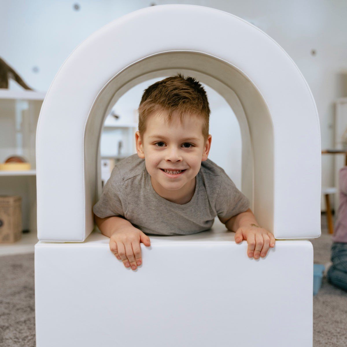7. Smiling boy crawling through white IGLU soft play tunnel in playroom