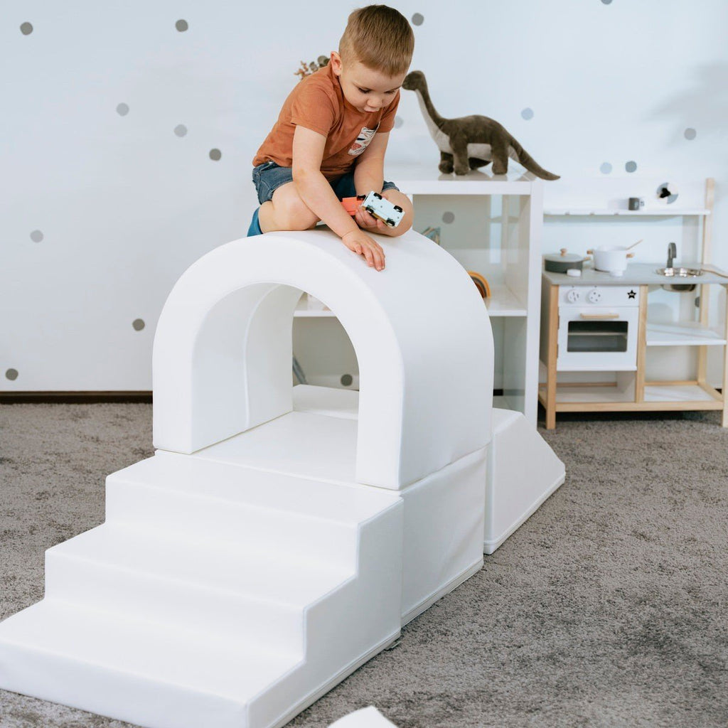 1. Child playing on white IGLU soft play tunnel set with steps in a playroom setting