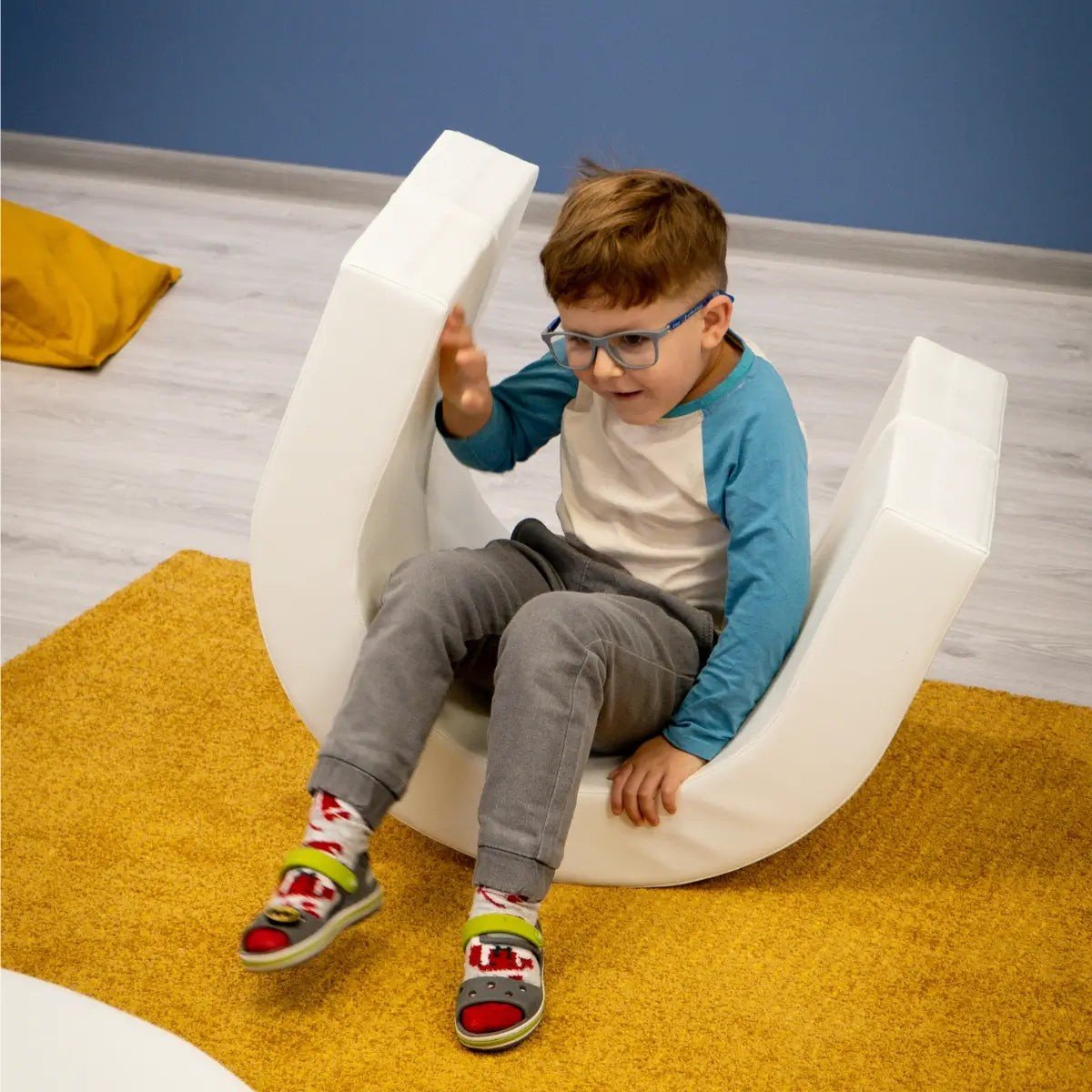 2. Boy sitting on curved white piece of IGLU soft play set on yellow rug
