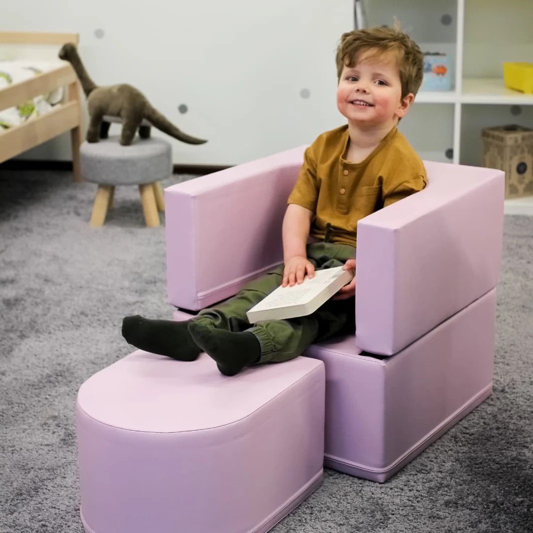1. Child sitting on pink IGLU Snoozy soft play sofa chair reading a book in a playroom