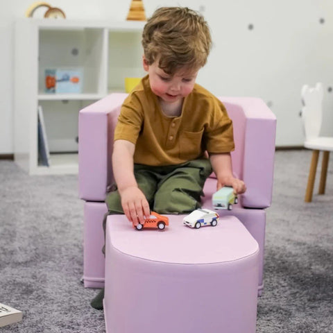 1. Child playing with toy cars on pink IGLU Snoozy soft play sofa chair in a playroom
