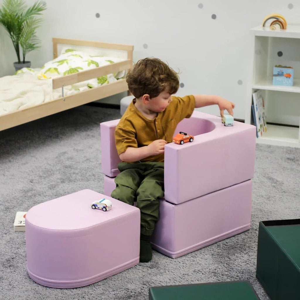 1. Child interacting with toy cars on pink IGLU Snoozy soft play sofa chair in a playroom