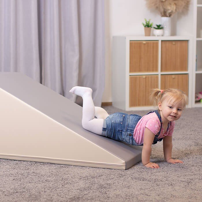 13. Toddler sliding down beige and grey soft play set in a modern living room