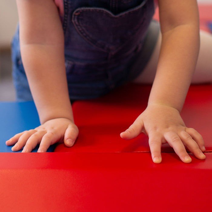 3. Close-up of toddler's hands on blue and red soft play set by IGLU