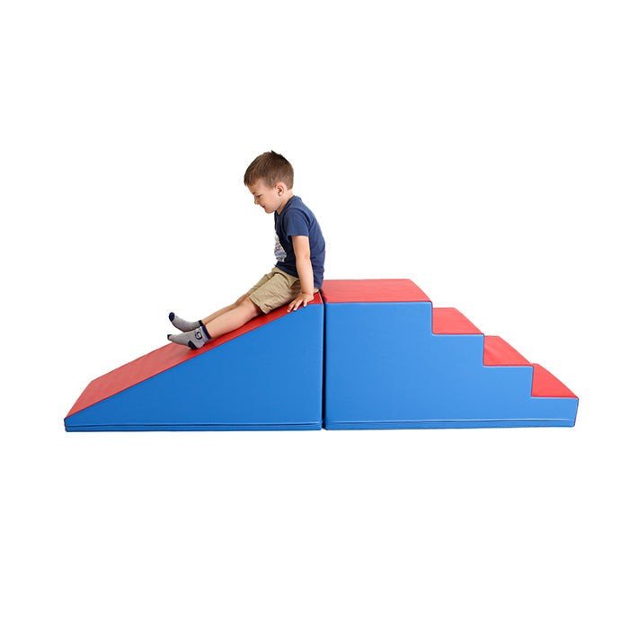 1. Boy sitting on blue and red soft play step and slide set by IGLU in a studio setting