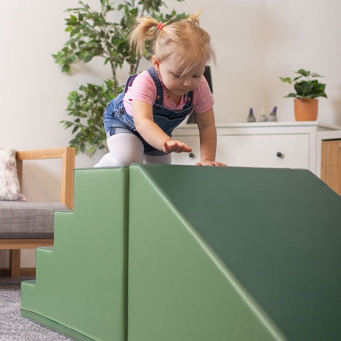 6. Child climbing green soft play set in a living room with plants and furniture